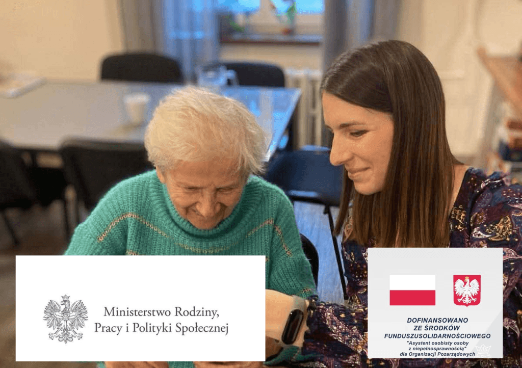Młoda asystentka pokazuje uśmiechniętej seniorce opaskę medyczną na jej nadgarstku.