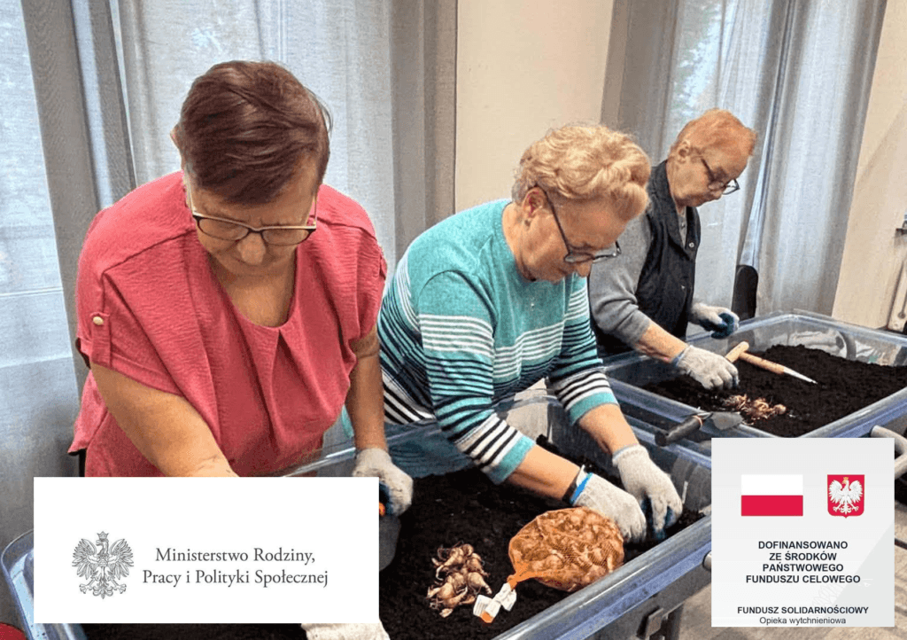 Trzy seniorki sadzące cebulki roślin w skrzyniach z ziemią podczas warsztatów.