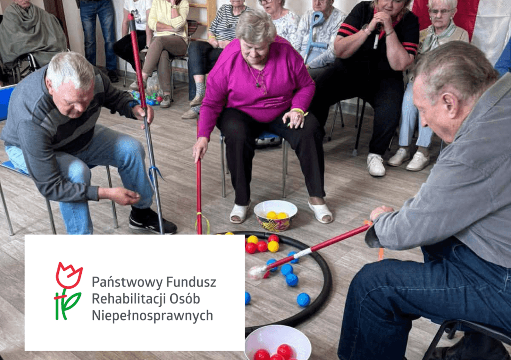 Seniorzy podczas grupowych gier zręcznościowych w sali oraz logo PFRON w lewym rogu.